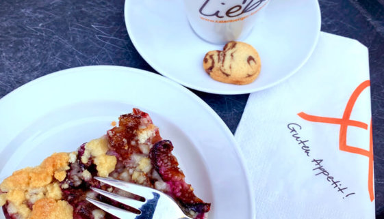 Stück Zwetschenkuchen auf Teller, ein Pot Kaffee mit Keks